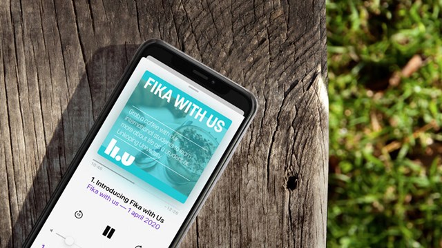 iPhone lying on a wooden bench outdoors with Fika with us podcast