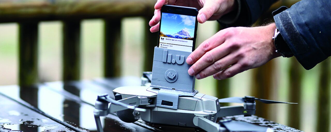 A pair of hands putting a cell phone on a drone