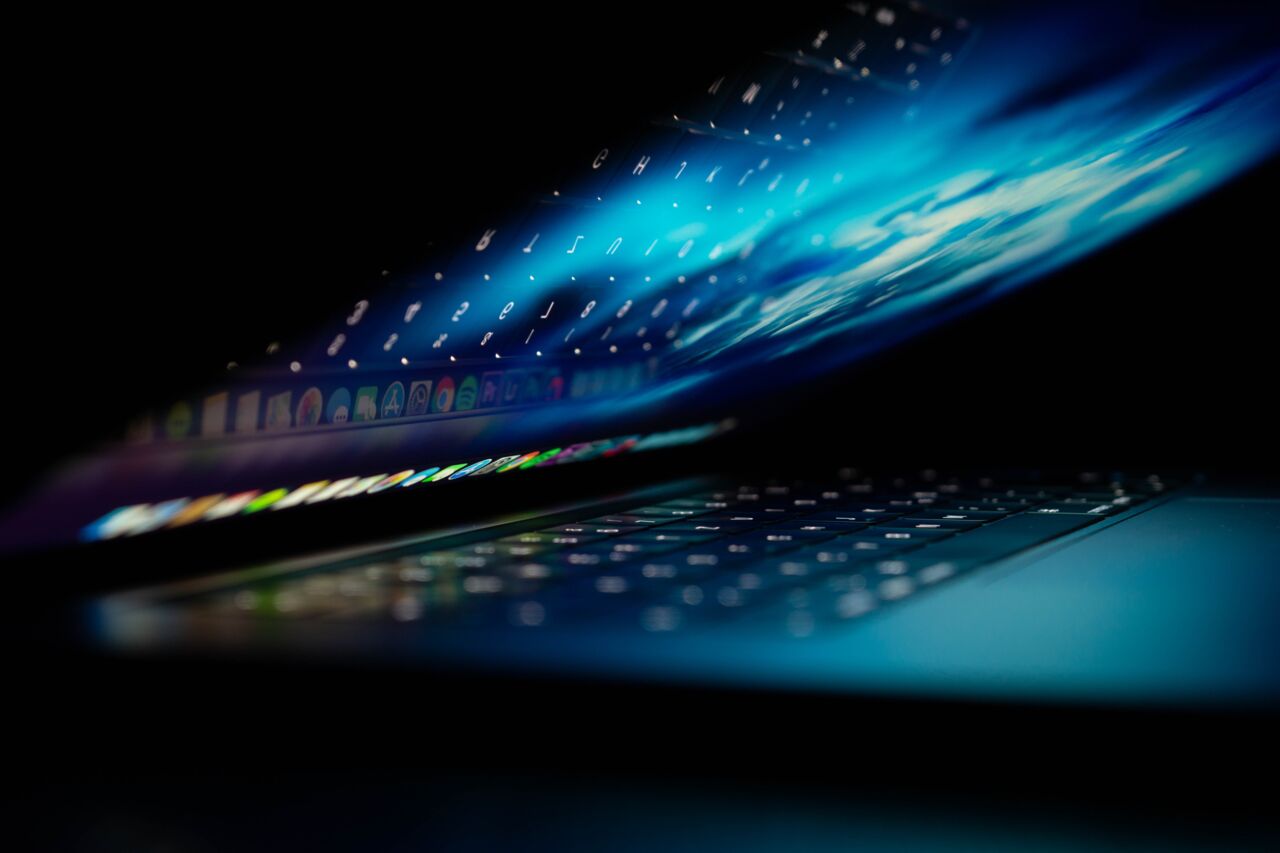 An almost folded laptop with a lit up screen and keyboard.