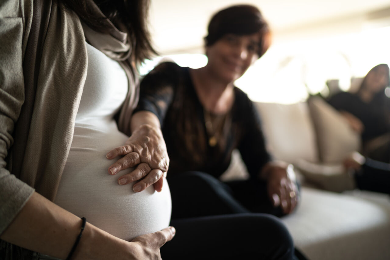 En gravid mage berörs av en annan persons hand