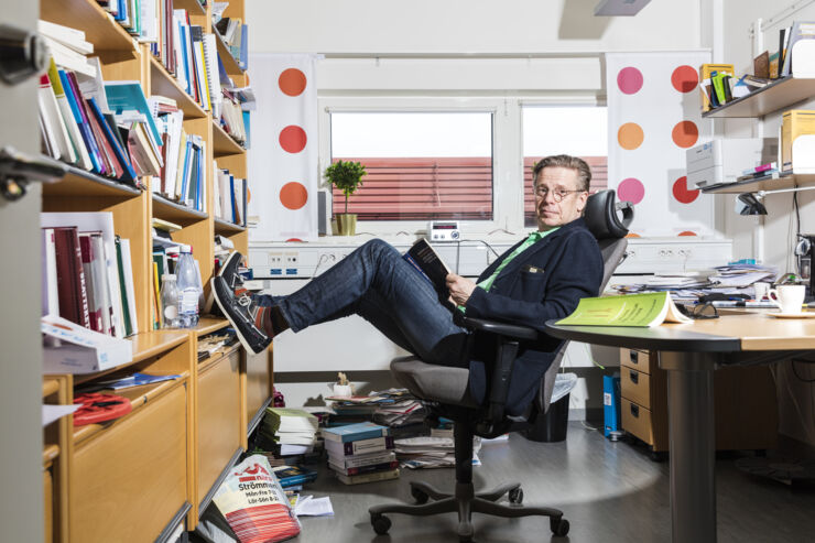 Jan Kellgren sitter bekvämt och läser en bok i sitt arbetsrum.