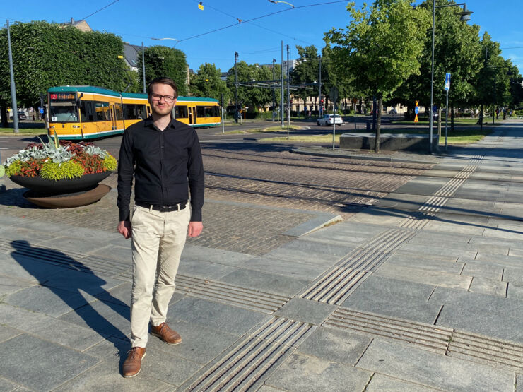 A man standing in front of tram tracks with a tram in the background