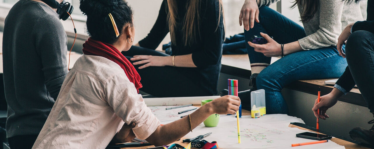 Bilden visar några ungdomar som sitter runt ett bord och studerar.
