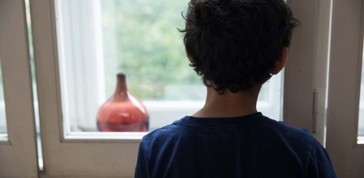 A lonely child looking out a window.