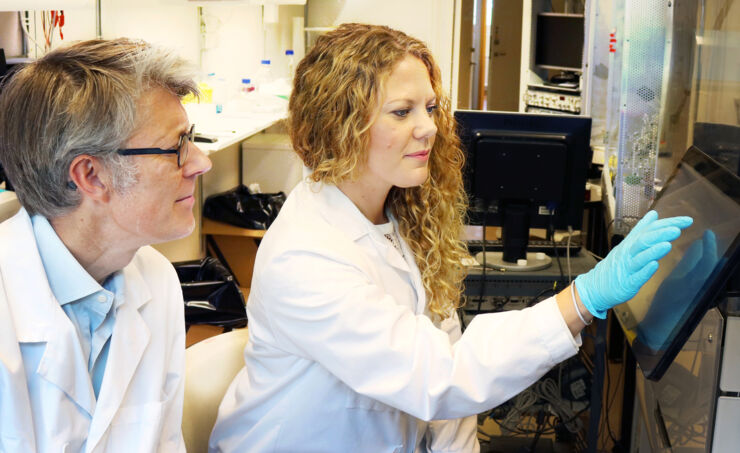 Male and female researchers sitting in lab + machine Qpatch 48..