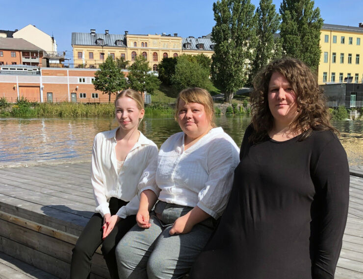 Tre kvinnor står framför Motala ström och Campus Norrköping. 