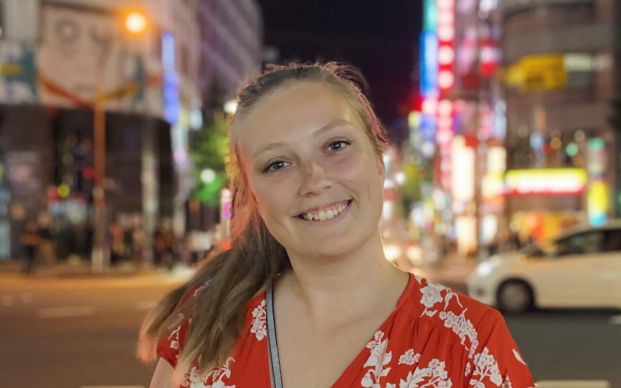 Jessica Pengel framför en fond av neonskyltar i Japan