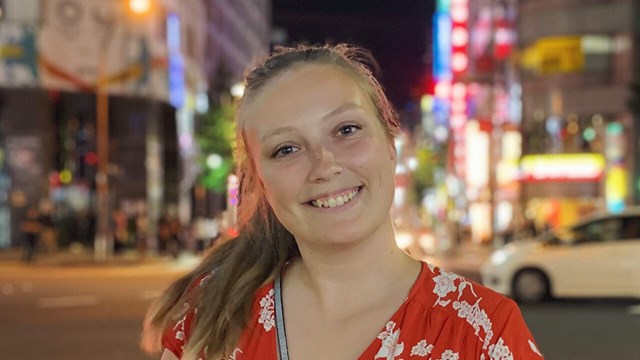 Jessica Pengel framför en fond av neonskyltar i Japan
