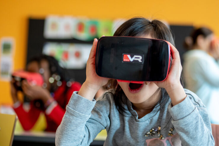 Barn har VR-headset framför ögonen och ser glad ut.