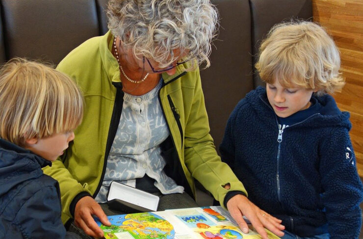 Förskollärare och elever tittar i en bok tillsammans.
