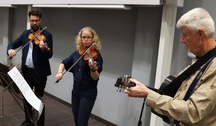 Liten orkester, tre personer spelar fiol och gitarr.