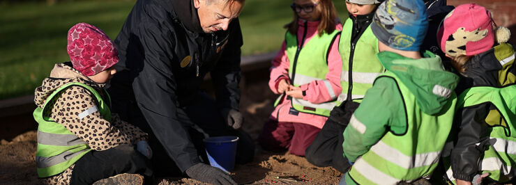 Förskollärare Henrik sitter och leker pedagogiskt med 6 barn i en sandlåda