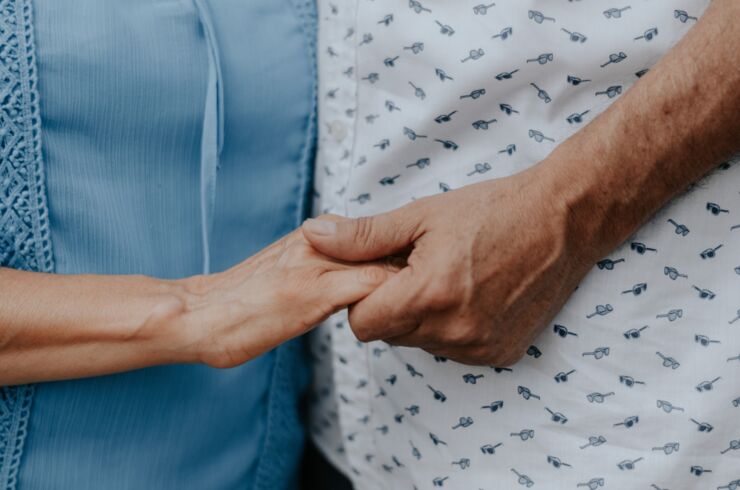 Närbild på två personer som håller i varandras hand. En ser bara de två händerna och personernas torso.