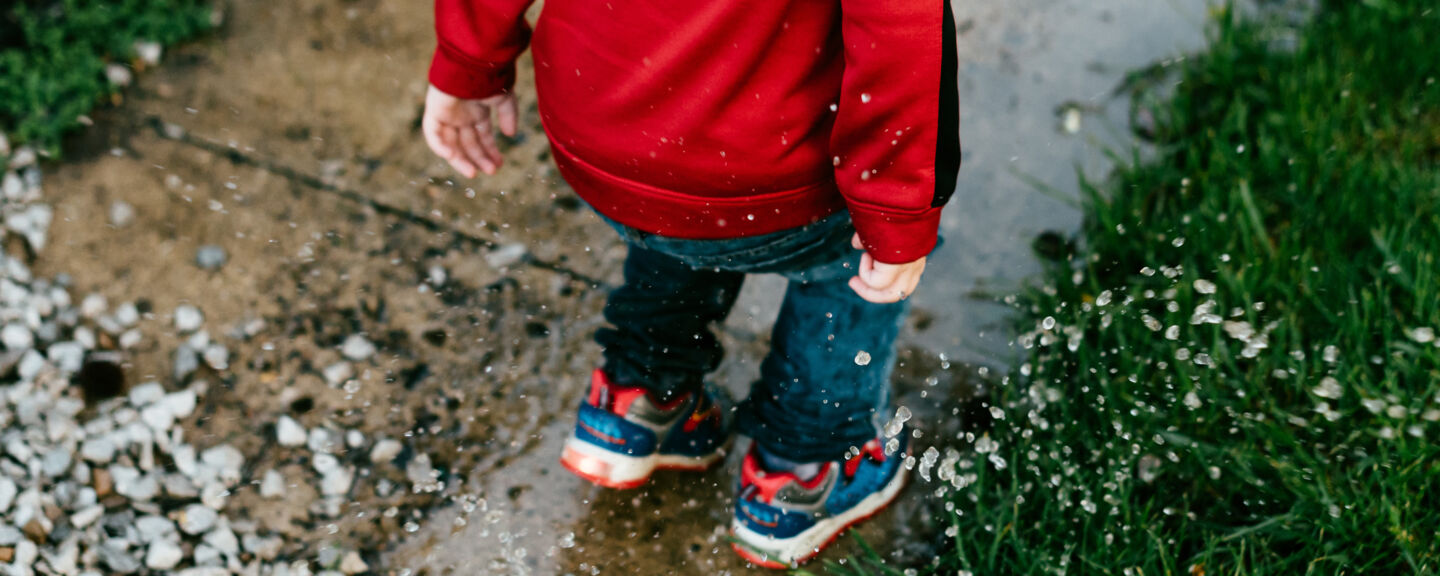 Close up of a kid who is jumping in a puddle. 