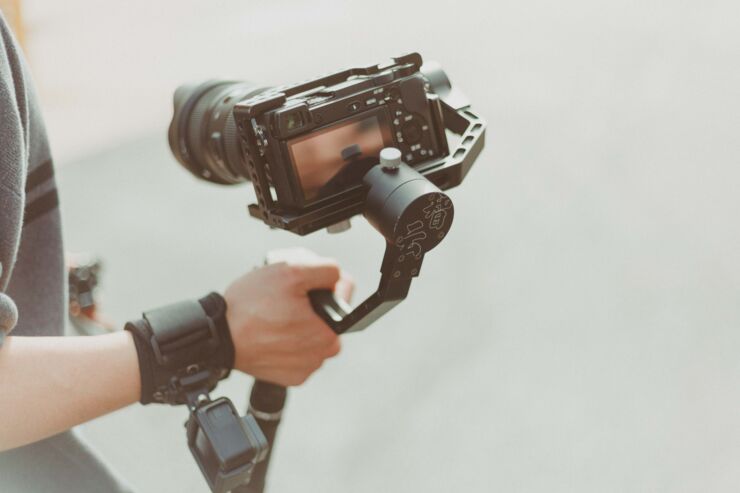 Person håller DSLR-kamera i handhållet stativ med GoPro på armen.