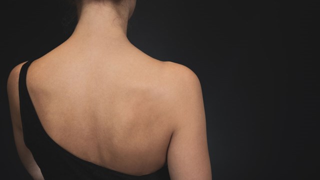 A woman's back. The background is black.