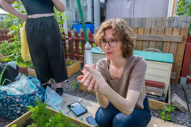 Geneviéve Metson collects water from bottles that the researchers have installed underneath garden plots.