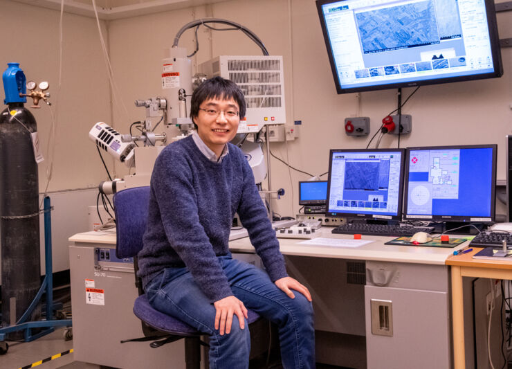 A young men in the lab, computerschreens in the background