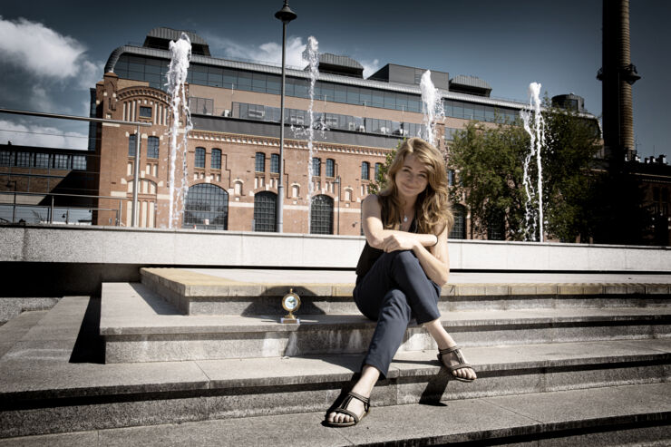 En helfigursbild av Natalia Oliwak som sitter på en trappa utomhus