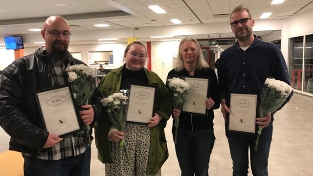 Fyra människor som fått pris diplom och blomma