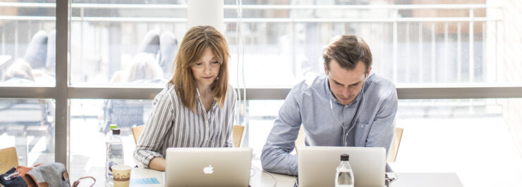 Två kvinnliga studenter vid ett bod framför ett fönster