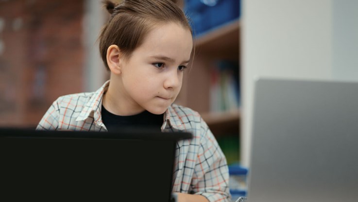 Boy using a laptop to program assembled robot from plastic bricks. STEM Education for kids.