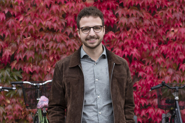 A portrait of a man in fron of a wall with red leaves