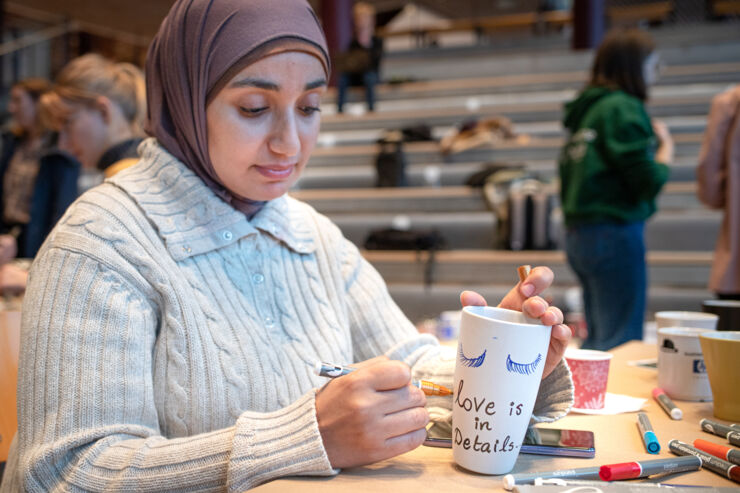 En kvinna målar en kaffemugg med pensel