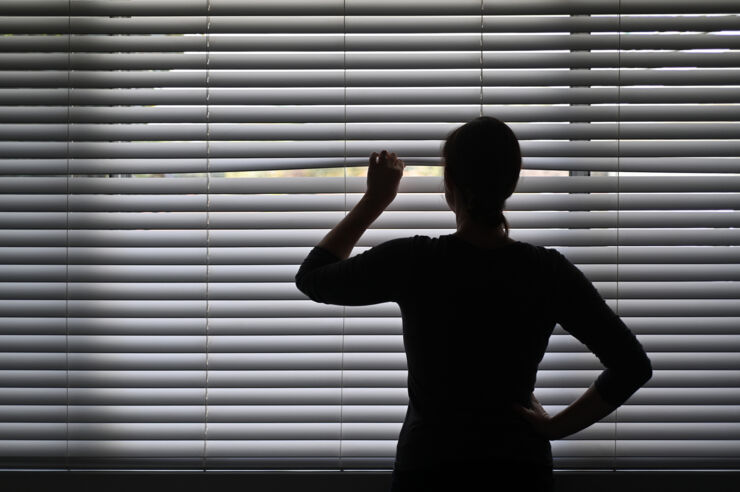 Woman in dark room, trying to look outside