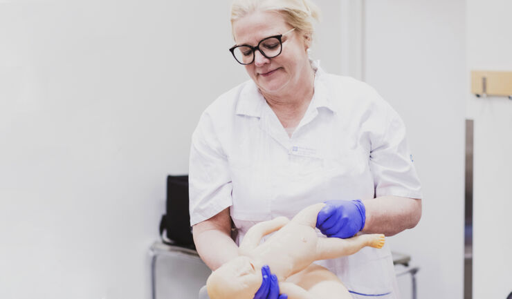 Female professor holding fake newborn baby for teaching.