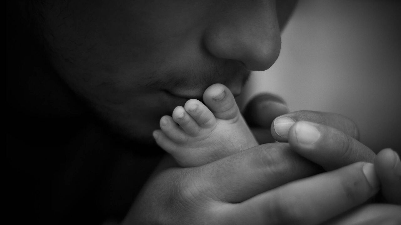 Adult tenderly holds a baby's foot