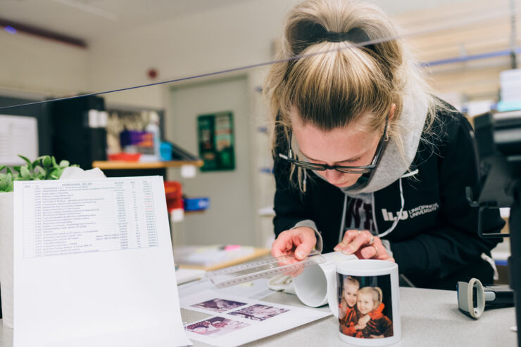 Young woman printing photos on mugs.