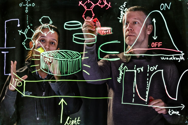 Akchheta Karki och Magnus Jonsson, två forskare bakom en glasskiva med figurer som visar hur antennerna kan styras.