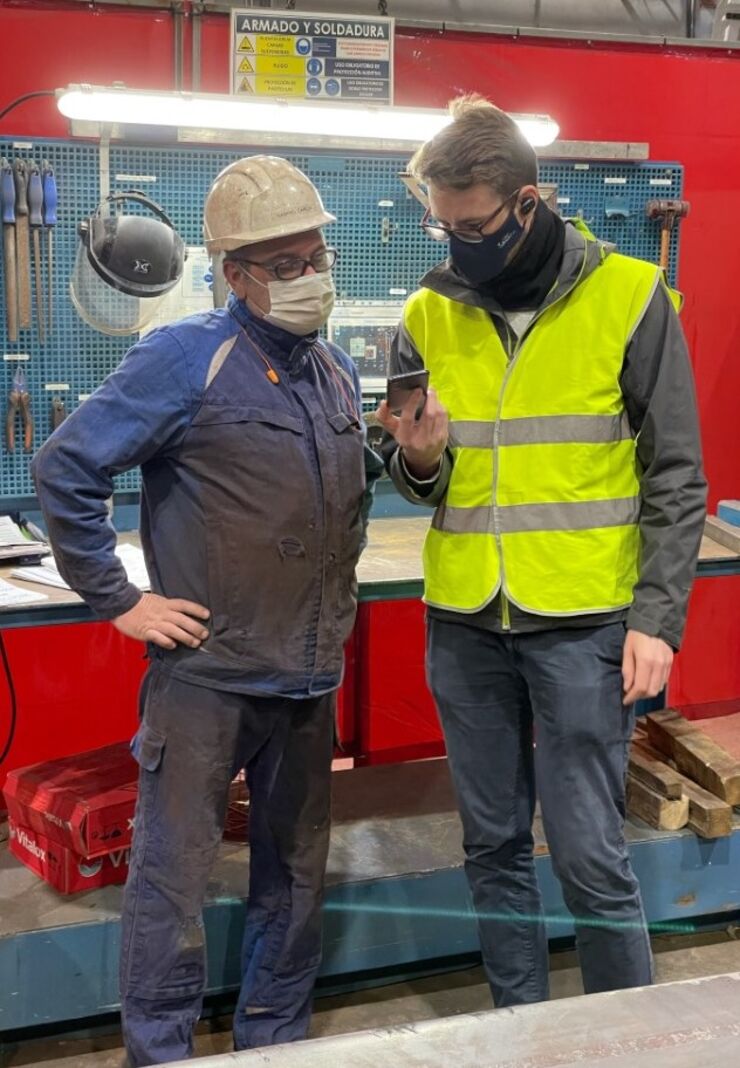 Två personer med munskydd i fabrik.