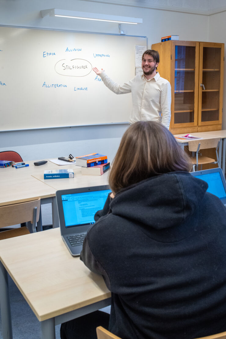 En person står framför tavlan i klassrummet. 