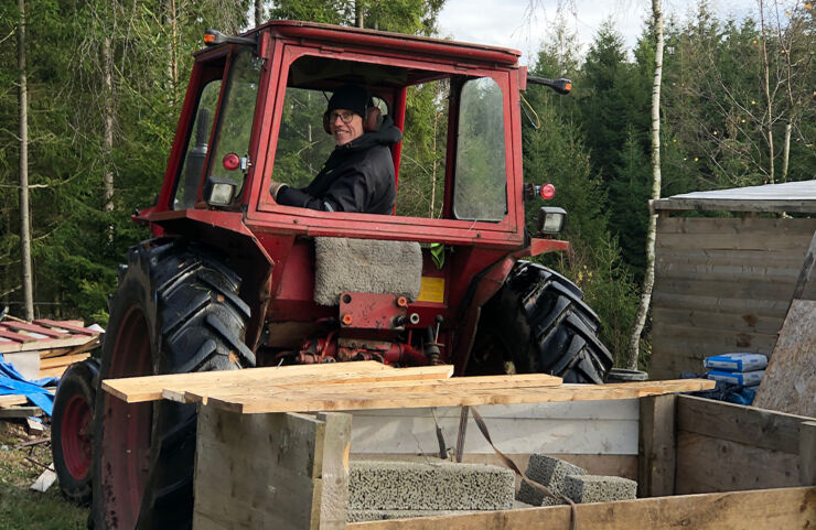 Torgny ler in i kameran sittandes i en röd traktor.