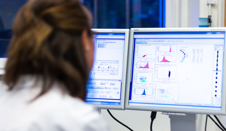 Kvinnlig forskare framför skärm med grafer och forskningsdata