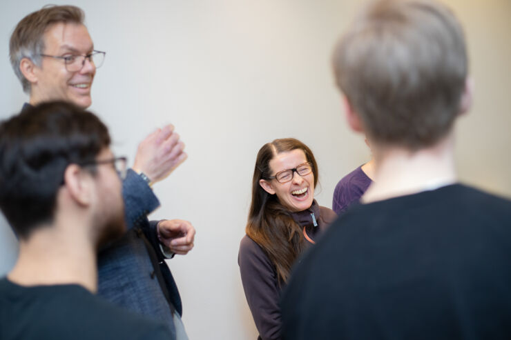 En grupp glada personer lyssnar på en som presenterar