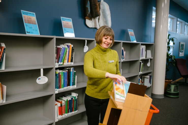 A librarian standing by a book shelf.