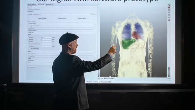 Gunnar Cedersund framför bild som illustrerar modellerna av olika organ.