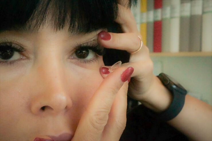 Close up of a woman inserting a contact lens in her eye.