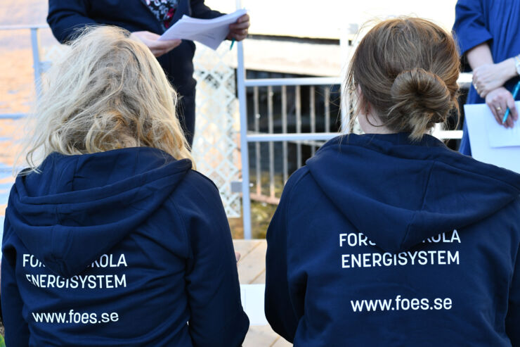 Två doktorander sitter ute med Forskarskola Energisystem tröjor på 