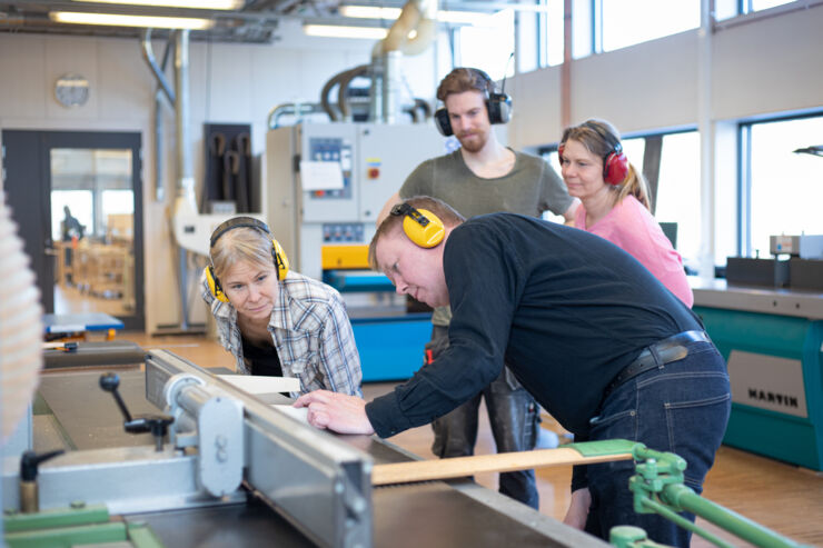 Lärare och studenter står vid ett arbetsredskap.