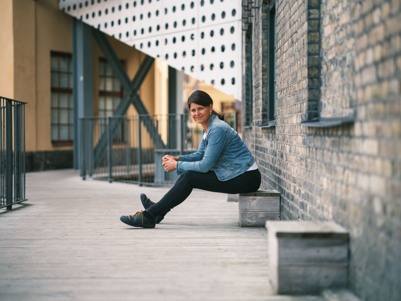 Josefina Syssner sitter framåtlutad vid en tegelvägg. 