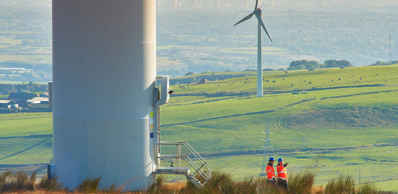 Två vindkraftsingenjörer lämnar dörren på ett vindkraftverk.