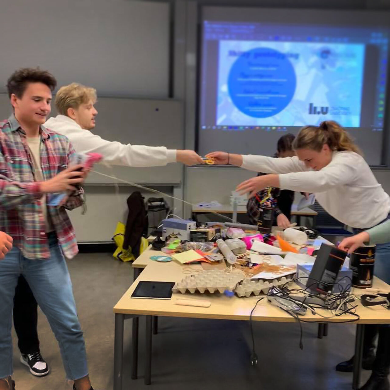 Studenter sitter runt ett bord och jobbar kreativ med uppgift