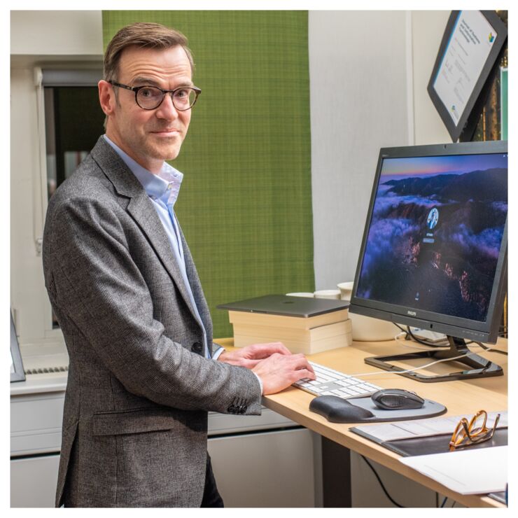 Professor Ulf Melin står vid sin arbetsplats och tittar in i kameran.