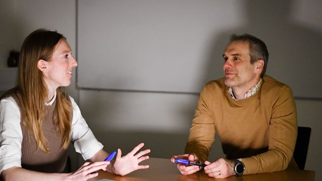 Två forskare  (en kvinna och en man) sitter vid bordet och diskuterar något