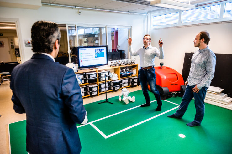 Mattias Tiger and Fredrik Löfgren are standing on the carpet with the minister in one of IDA's robotic laboratories.