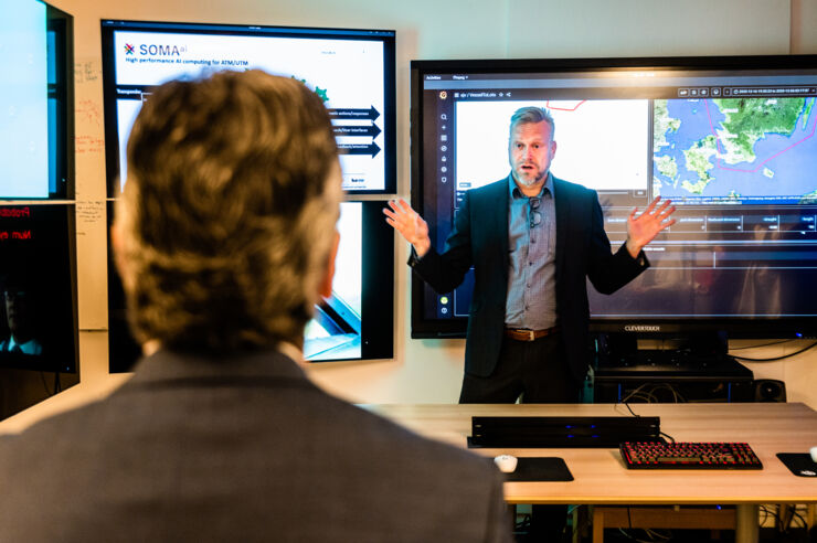 Magnus Bång stands in front of some big screens speaking about articial intelligence in transport systems.